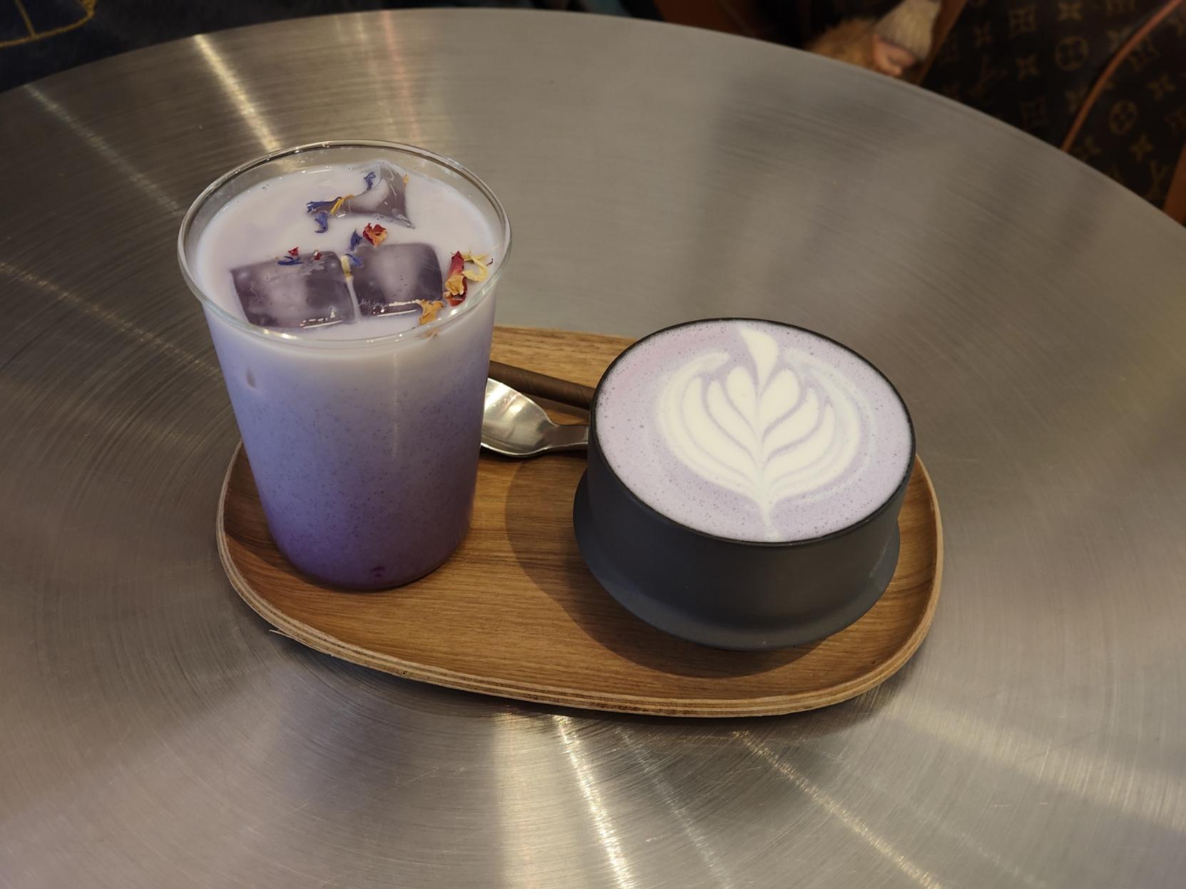 a photo of two purple teas with milk, one iced and one not.